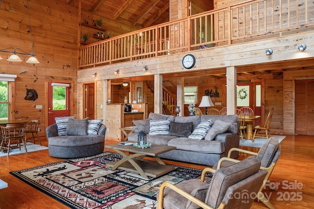 living room with wood finished floors, wooden walls, high vaulted ceiling, and wooden ceiling