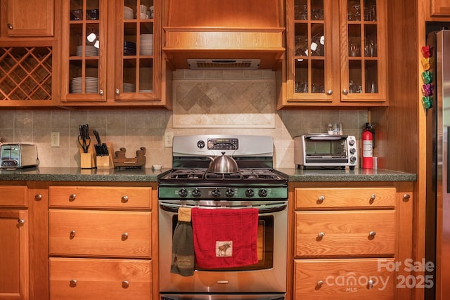 kitchen featuring glass insert cabinets, backsplash, a toaster, and stainless steel appliances