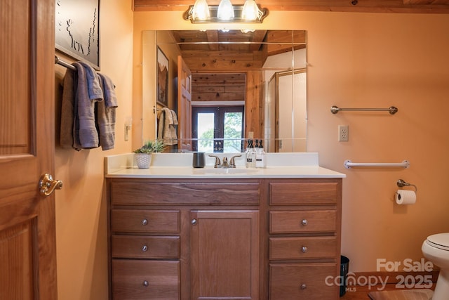 full bathroom featuring vanity, a stall shower, toilet, and french doors