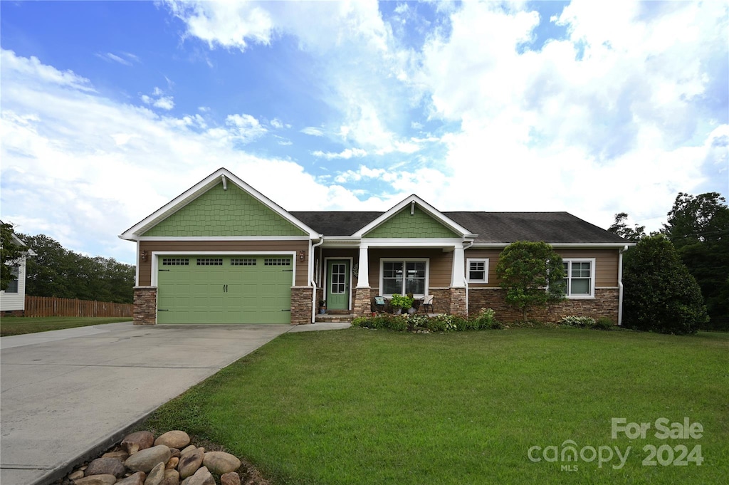 craftsman-style house featuring covered porch, a garage, and a front lawn