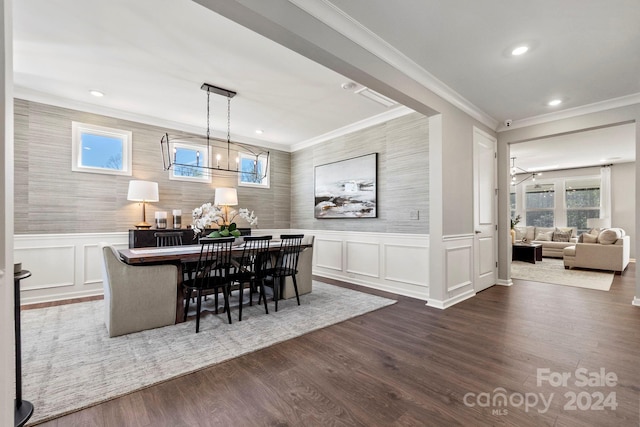 dining space with dark hardwood / wood-style flooring, crown molding, and a chandelier