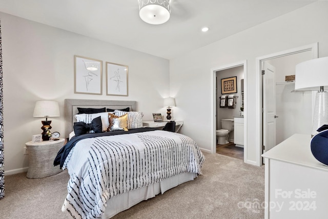 bedroom featuring ensuite bath, light colored carpet, a closet, and a walk in closet