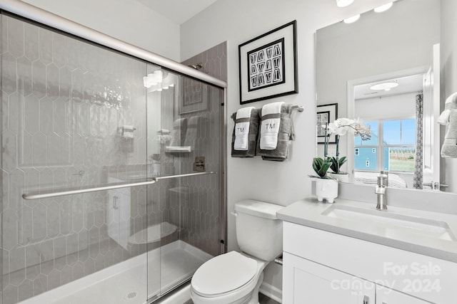 bathroom featuring toilet, a shower with door, and vanity