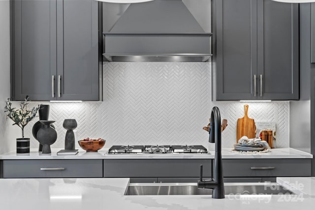 kitchen featuring gray cabinetry, custom exhaust hood, tasteful backsplash, and light stone counters