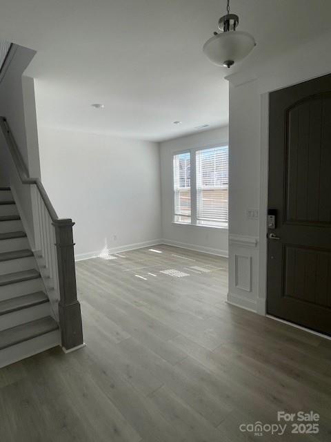 interior space with wood finished floors, baseboards, and stairs