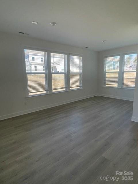 spare room with baseboards, dark wood-type flooring, and a wealth of natural light