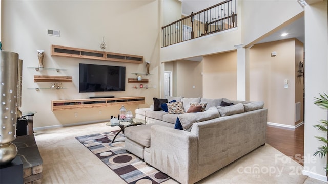 living room featuring wood-type flooring, decorative columns, and a high ceiling