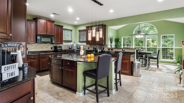 kitchen featuring dark stone countertops, hanging light fixtures, black appliances, and a kitchen island