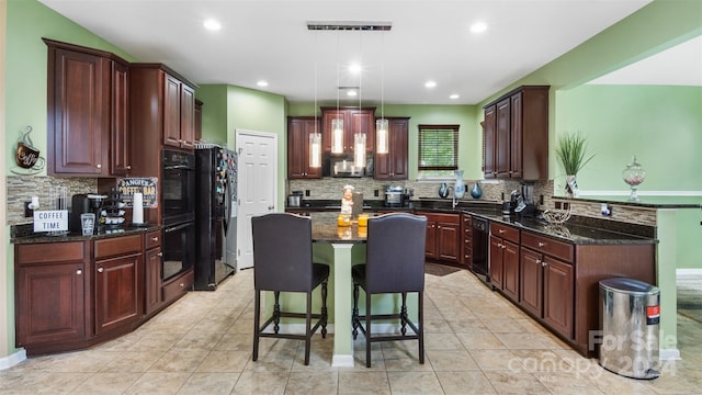 kitchen featuring a breakfast bar area, decorative light fixtures, a center island, dark stone countertops, and black appliances