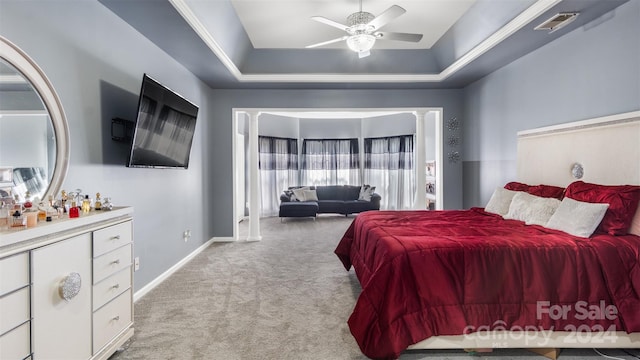 bedroom with light carpet, a tray ceiling, and ceiling fan