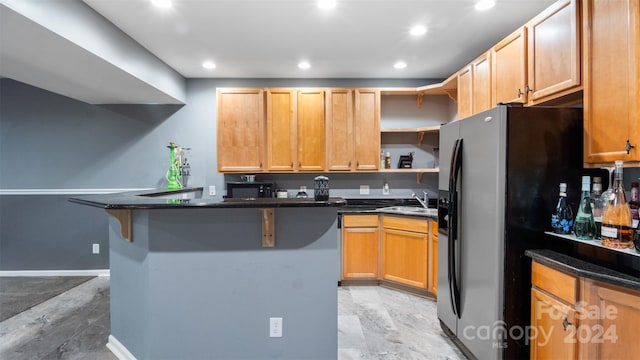 kitchen with sink, black appliances, kitchen peninsula, and a kitchen bar