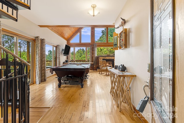 recreation room with wood ceiling, light hardwood / wood-style floors, a stone fireplace, pool table, and lofted ceiling with beams