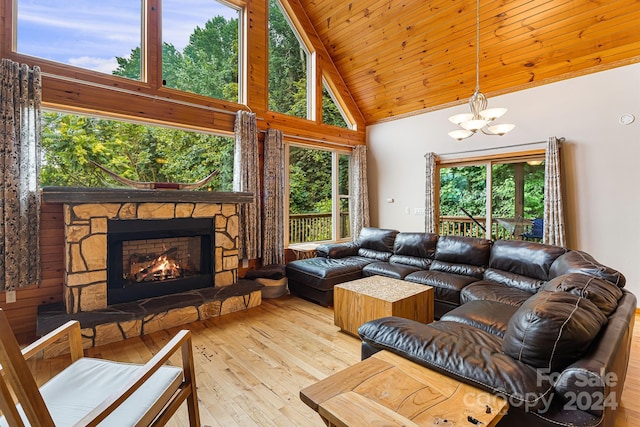 living room with wood ceiling, a stone fireplace, light hardwood / wood-style floors, a notable chandelier, and high vaulted ceiling