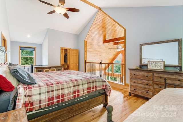 bedroom with ceiling fan, a walk in closet, vaulted ceiling, and light wood-type flooring