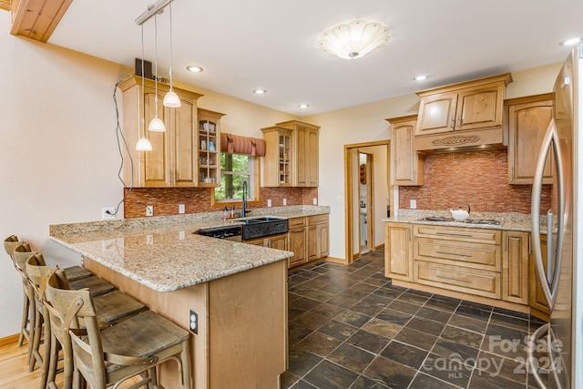 kitchen with light stone countertops, decorative light fixtures, a kitchen breakfast bar, sink, and kitchen peninsula