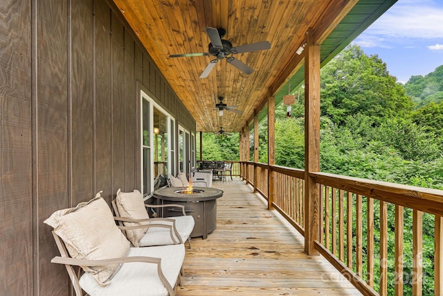 wooden terrace with ceiling fan and an outdoor fire pit