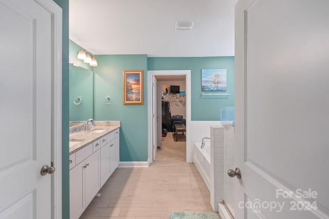 bathroom with vanity, wood-type flooring, and tiled tub