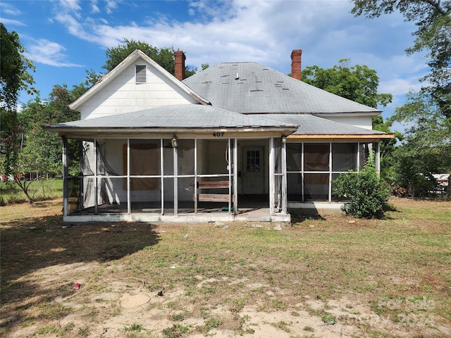 rear view of property with a yard and a sunroom