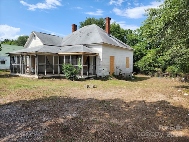 rear view of house featuring a sunroom and a yard