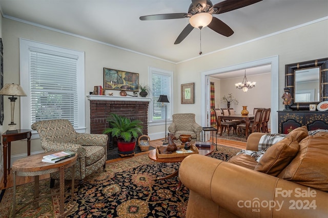 living room with ceiling fan with notable chandelier, hardwood / wood-style flooring, crown molding, and a fireplace