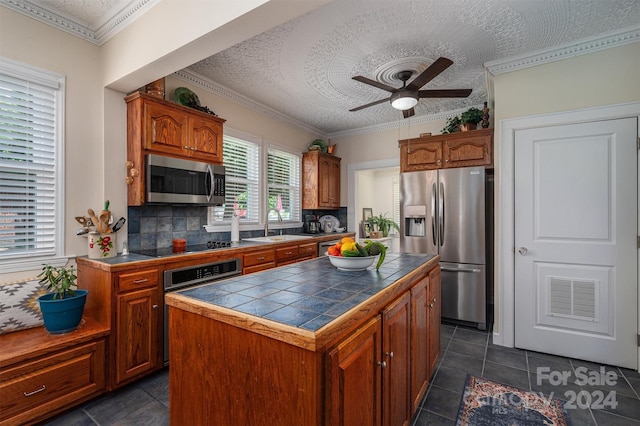 kitchen featuring tasteful backsplash, a center island, sink, stainless steel appliances, and tile counters