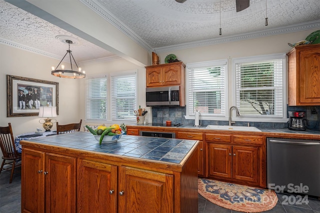 kitchen featuring a kitchen island, decorative light fixtures, stainless steel appliances, sink, and backsplash