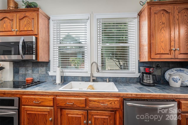 kitchen with appliances with stainless steel finishes, decorative backsplash, tile counters, and sink