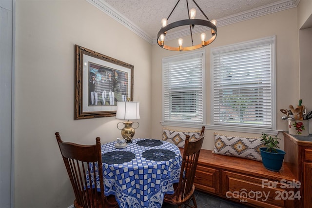 dining area with a textured ceiling, ornamental molding, dark tile patterned flooring, and a notable chandelier