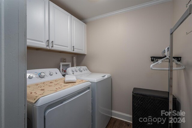 clothes washing area featuring washing machine and dryer, cabinets, dark hardwood / wood-style flooring, and crown molding