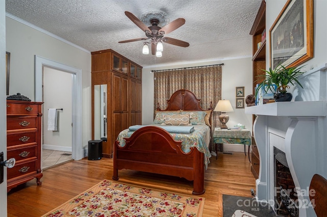 bedroom featuring ceiling fan, crown molding, a textured ceiling, and light hardwood / wood-style flooring