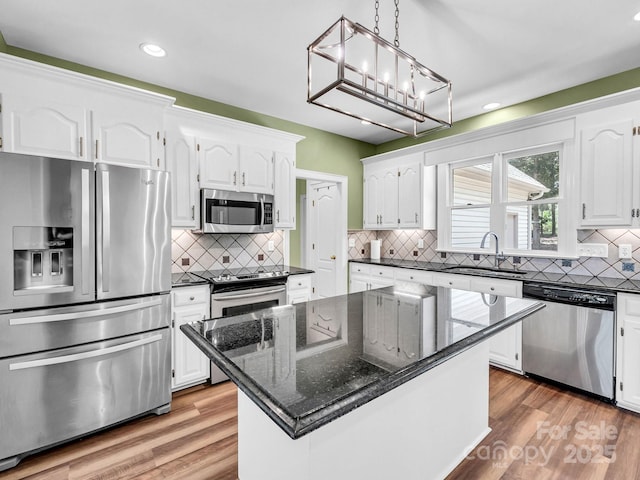 kitchen featuring hardwood / wood-style flooring, appliances with stainless steel finishes, a center island, white cabinets, and sink