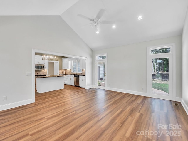 unfurnished living room with high vaulted ceiling, ceiling fan, a wealth of natural light, and light hardwood / wood-style floors