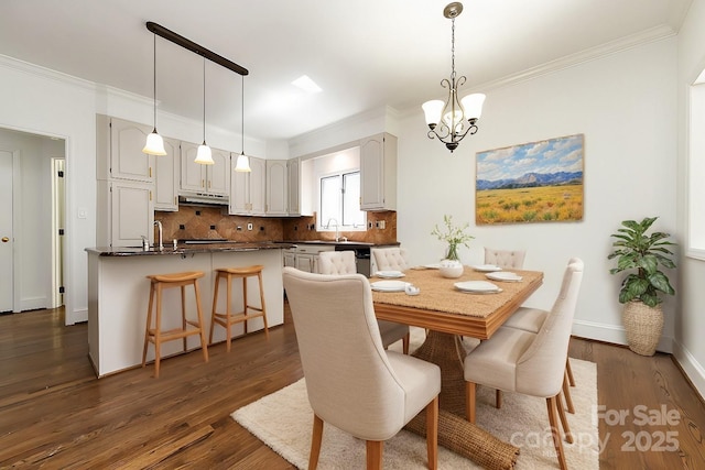 dining room featuring sink, dark hardwood / wood-style floors, crown molding, and a chandelier