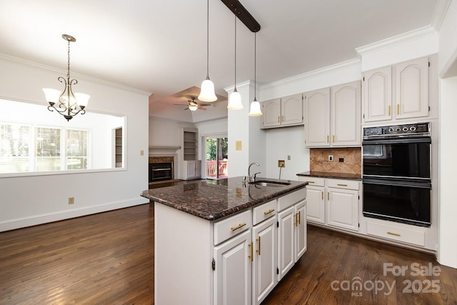 kitchen with ceiling fan with notable chandelier, white cabinets, decorative light fixtures, decorative backsplash, and sink