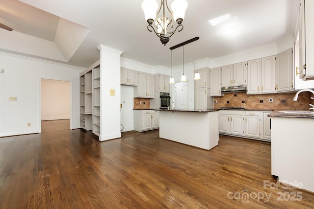 kitchen featuring an inviting chandelier, white cabinetry, tasteful backsplash, a kitchen island, and sink