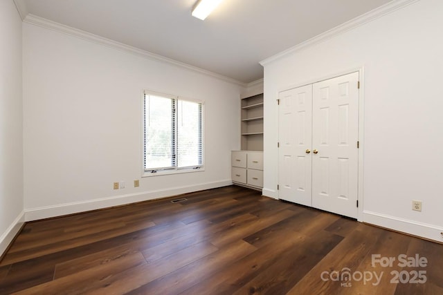 unfurnished bedroom featuring a closet, dark wood-type flooring, and crown molding