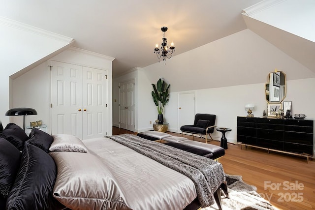 bedroom featuring hardwood / wood-style flooring, crown molding, lofted ceiling, and a chandelier