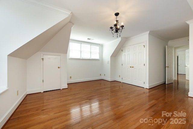 bonus room featuring a notable chandelier and hardwood / wood-style flooring