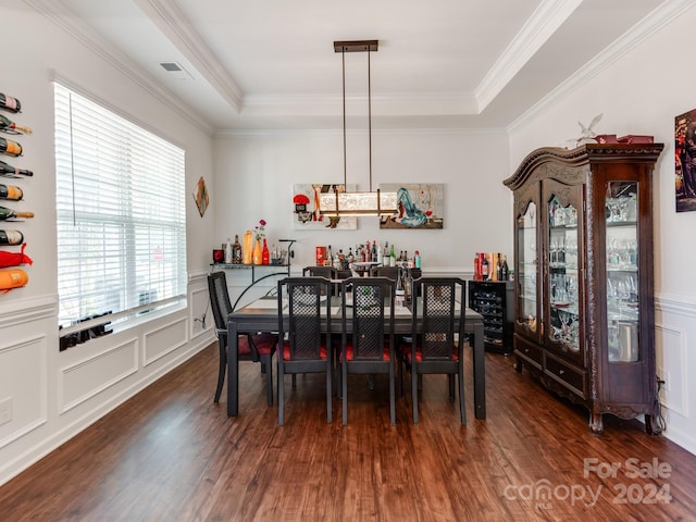 dining area featuring dark wood-type flooring, a tray ceiling, and ornamental molding