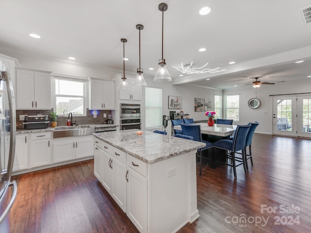 kitchen with white cabinetry, tasteful backsplash, a center island, hanging light fixtures, and sink