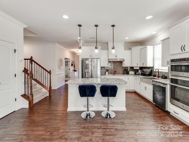 kitchen featuring hanging light fixtures, appliances with stainless steel finishes, white cabinets, and a kitchen island