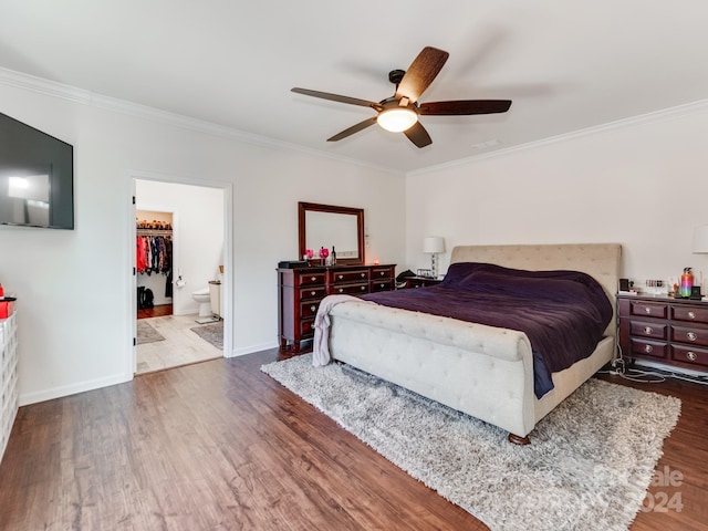 bedroom with a walk in closet, dark hardwood / wood-style floors, a closet, ceiling fan, and crown molding