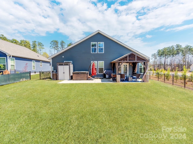 rear view of property with a hot tub, a yard, and a patio