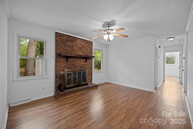 unfurnished living room featuring a brick fireplace, plenty of natural light, hardwood / wood-style floors, and a textured ceiling