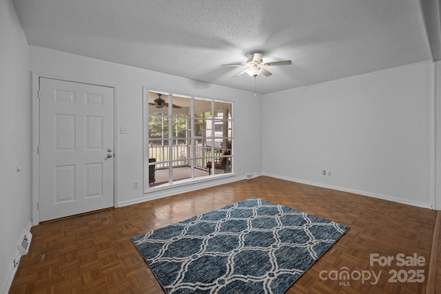 interior space featuring dark parquet flooring, a textured ceiling, and ceiling fan