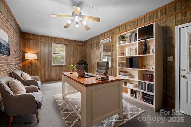 carpeted office with ceiling fan and wood walls