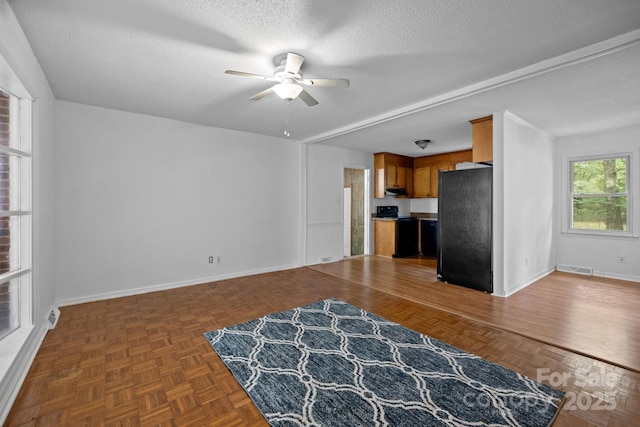 unfurnished living room featuring ceiling fan, dark parquet floors, and a textured ceiling