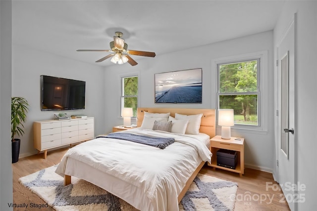 bedroom with ceiling fan, light hardwood / wood-style floors, and multiple windows