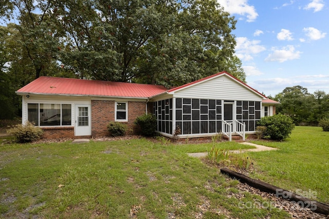 back of house with a sunroom and a lawn