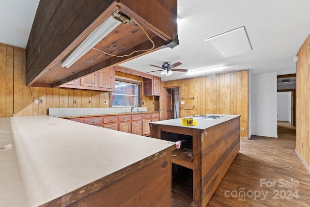 kitchen with ceiling fan, sink, dark hardwood / wood-style flooring, a textured ceiling, and wooden walls